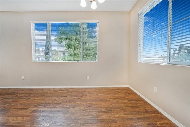 empty room with wood finished floors, baseboards, and a wealth of natural light