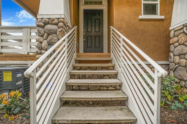 doorway to property with stucco siding and central AC