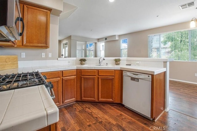 kitchen with visible vents, dark wood finished floors, white dishwasher, stainless steel microwave, and brown cabinets