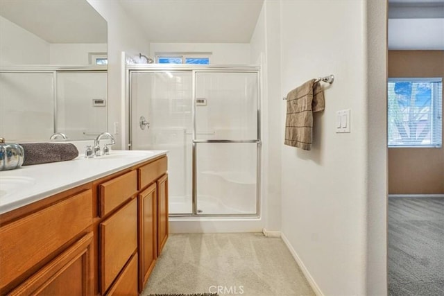 bathroom featuring double vanity, a stall shower, baseboards, and a sink