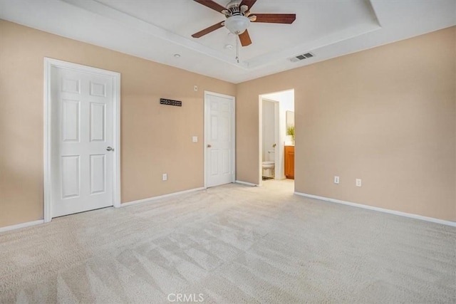 unfurnished bedroom with a raised ceiling, baseboards, visible vents, and light carpet