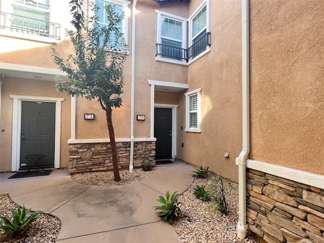 view of exterior entry with stone siding and stucco siding