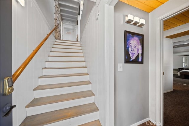 stairway featuring baseboards and carpet flooring