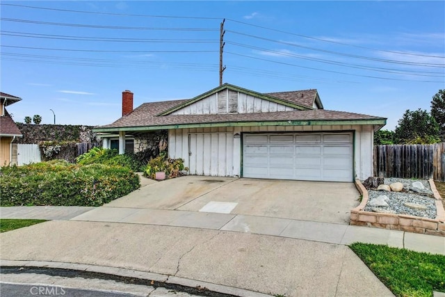 view of front of house with a chimney, concrete driveway, an attached garage, and fence