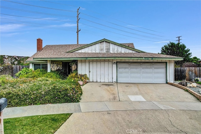 view of front facade with concrete driveway, fence, a garage, and a chimney