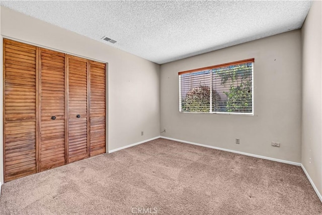 unfurnished bedroom featuring visible vents, baseboards, carpet flooring, a closet, and a textured ceiling