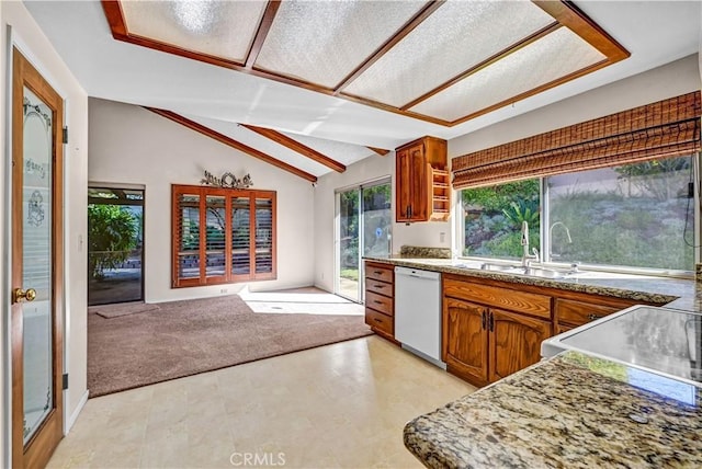 kitchen featuring open floor plan, lofted ceiling, light carpet, brown cabinets, and white dishwasher