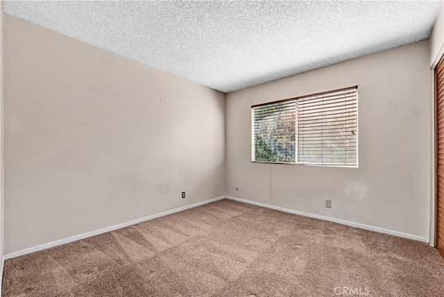 empty room with a textured ceiling, baseboards, and carpet floors