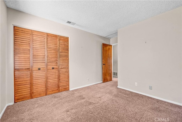 unfurnished bedroom with visible vents, baseboards, carpet floors, a closet, and a textured ceiling