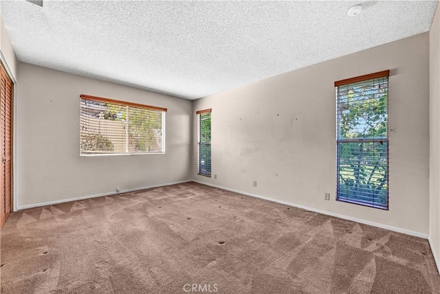 unfurnished room with a textured ceiling, baseboards, and carpet