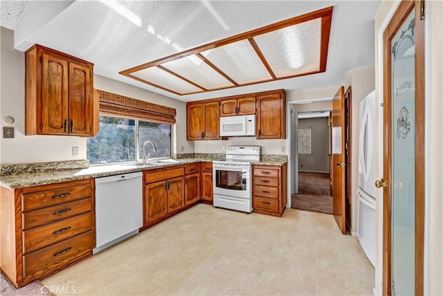 kitchen featuring a sink, white appliances, light floors, and brown cabinetry