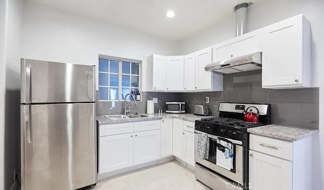 kitchen featuring backsplash, under cabinet range hood, appliances with stainless steel finishes, white cabinets, and a sink