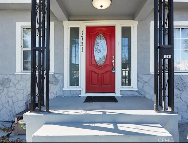 view of exterior entry featuring stone siding and stucco siding