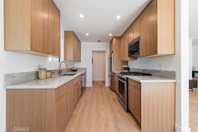 kitchen featuring light wood finished floors, a sink, recessed lighting, stainless steel appliances, and light countertops