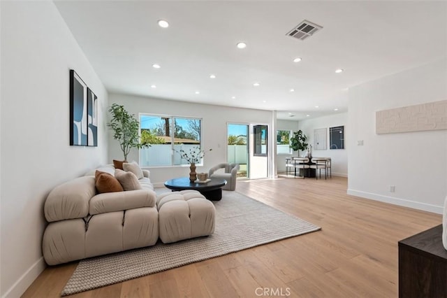 living room featuring light wood finished floors, visible vents, recessed lighting, and baseboards