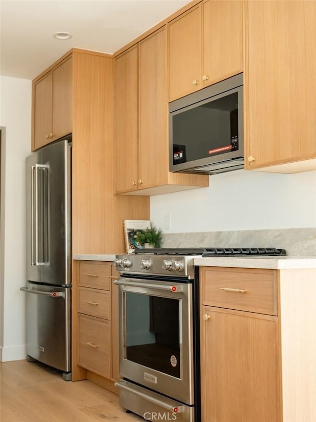 kitchen with light brown cabinetry, high quality appliances, and light countertops