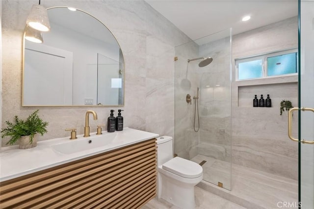 bathroom featuring tile walls, toilet, vanity, and a shower with shower door