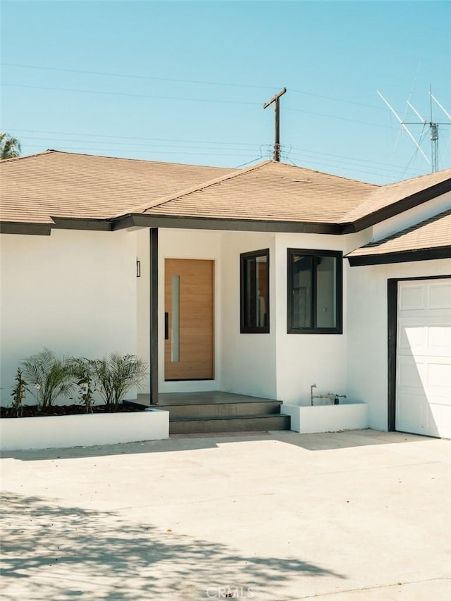 view of front of home featuring a shingled roof, concrete driveway, a garage, and stucco siding