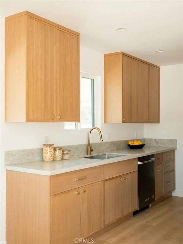 kitchen with a sink, light wood-type flooring, light brown cabinetry, and light countertops