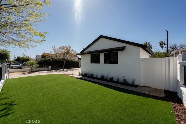 view of side of property with a yard, a fenced backyard, and stucco siding