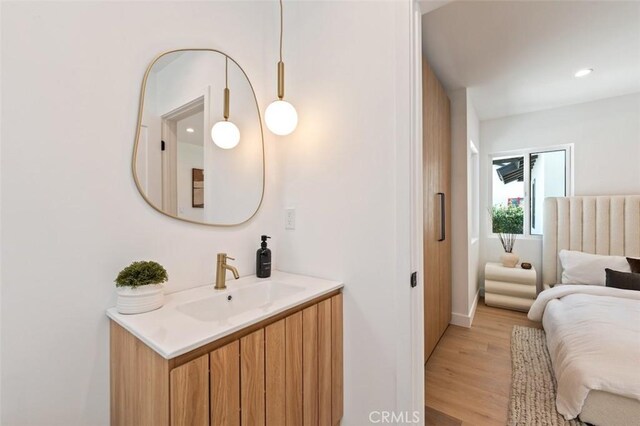 bathroom with recessed lighting, wood finished floors, and vanity