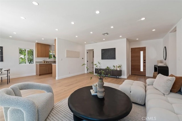 living area featuring visible vents, recessed lighting, baseboards, and light wood finished floors