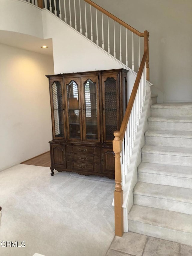 stairway with a high ceiling, recessed lighting, and carpet