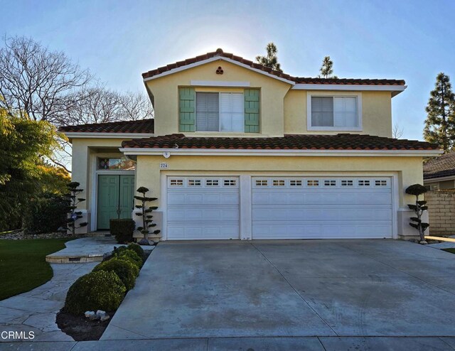 traditional-style home featuring stucco siding, an attached garage, a tile roof, and driveway