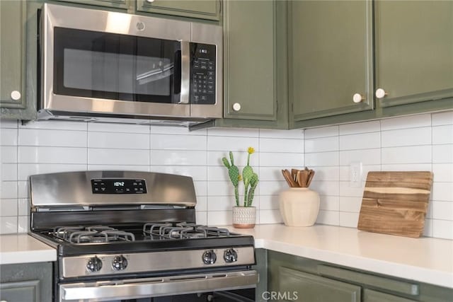 kitchen with stainless steel appliances, tasteful backsplash, green cabinets, and light countertops