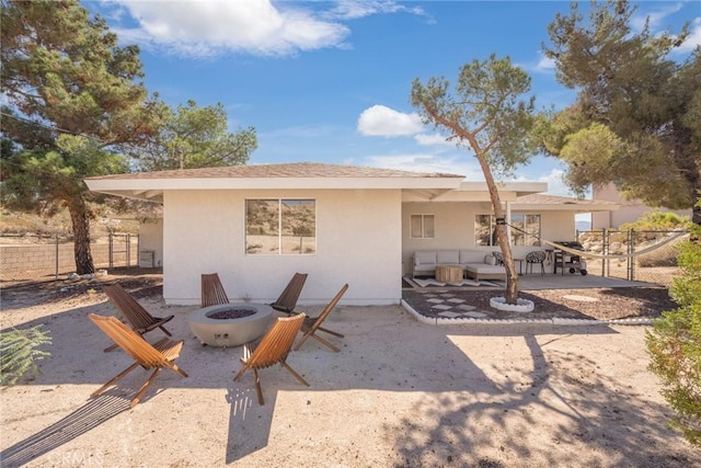 rear view of property with stucco siding, a patio, a fire pit, and fence