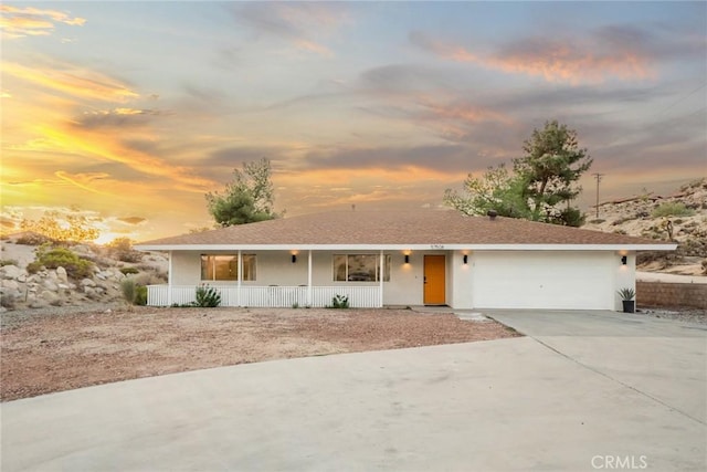 single story home with stucco siding, driveway, a porch, and an attached garage