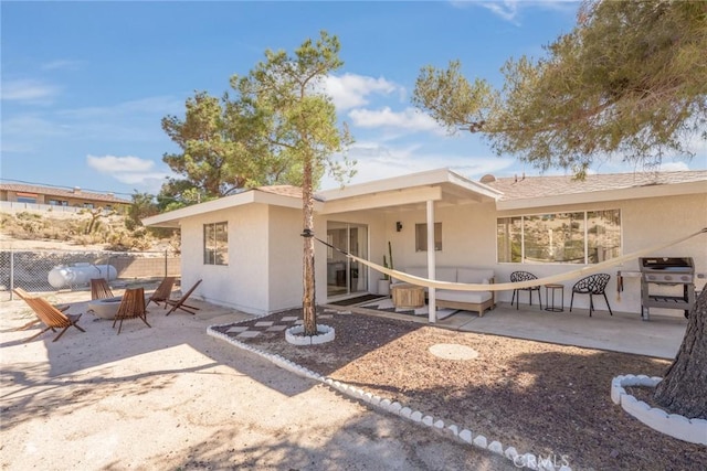 rear view of house featuring a patio, fence, and stucco siding