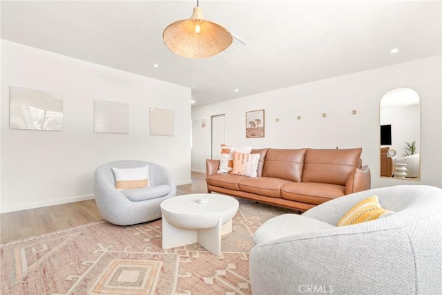 living area with arched walkways, recessed lighting, light wood-type flooring, and baseboards