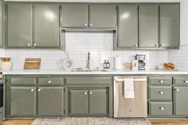 kitchen featuring green cabinets, light countertops, stainless steel dishwasher, and a sink