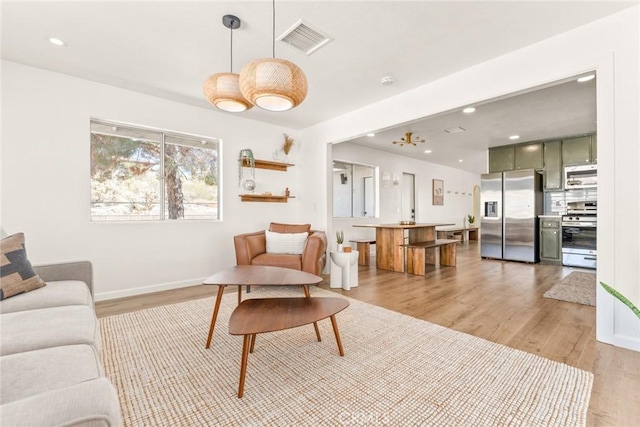 living area with recessed lighting, visible vents, light wood finished floors, and baseboards