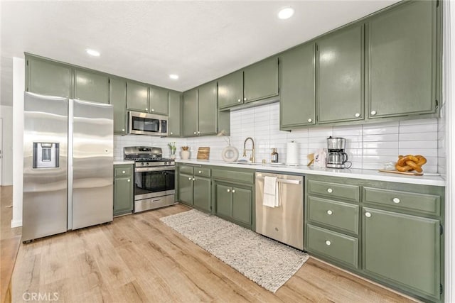 kitchen with a sink, appliances with stainless steel finishes, green cabinets, and light countertops