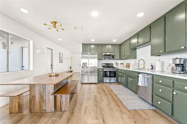 kitchen with a sink, decorative backsplash, stainless steel appliances, and green cabinetry