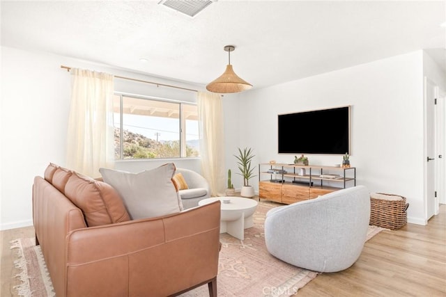 living area featuring wood finished floors, visible vents, and baseboards