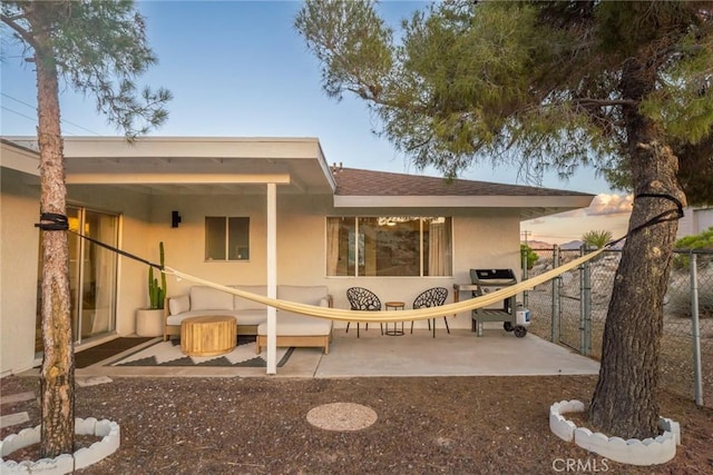 rear view of property featuring stucco siding, a patio area, a shingled roof, and fence