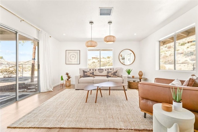 living area with a wealth of natural light, visible vents, wood finished floors, and recessed lighting