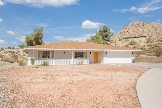 ranch-style house featuring stucco siding, a porch, driveway, and a garage