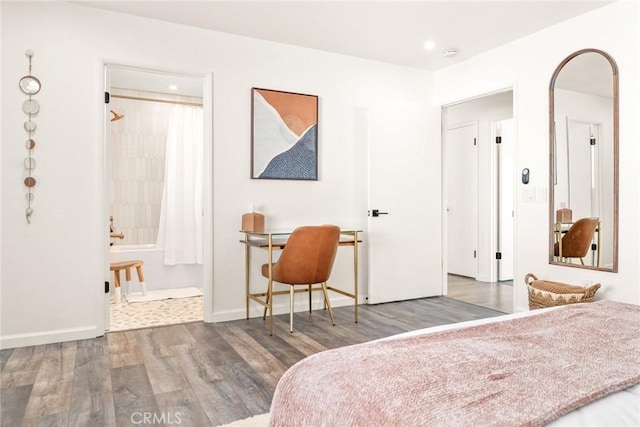 bedroom with arched walkways, wood finished floors, baseboards, and connected bathroom