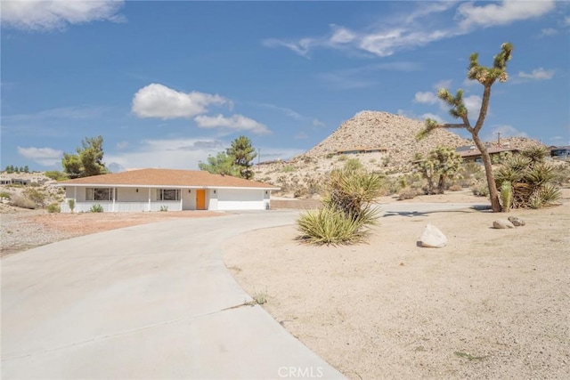 ranch-style house with concrete driveway, an attached garage, and covered porch