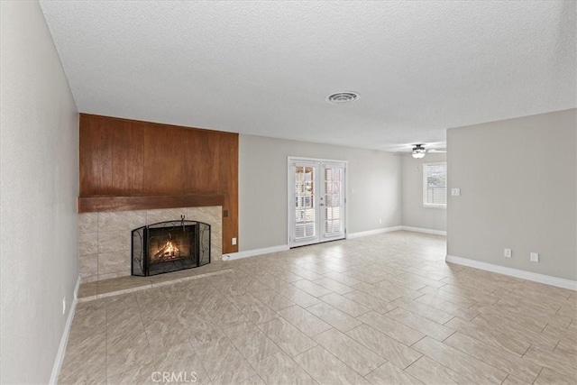 unfurnished living room with visible vents, a ceiling fan, a textured ceiling, french doors, and a large fireplace