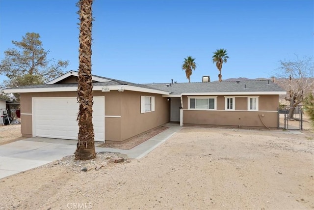 ranch-style home with stucco siding, a garage, and driveway