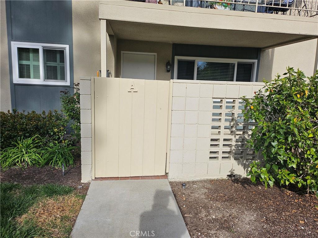 entrance to property with concrete block siding, a gate, fence, and stucco siding