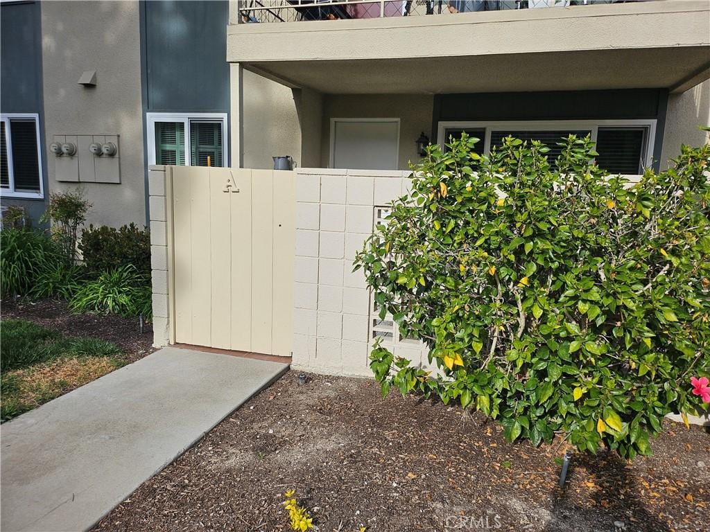 view of exterior entry with fence and stucco siding