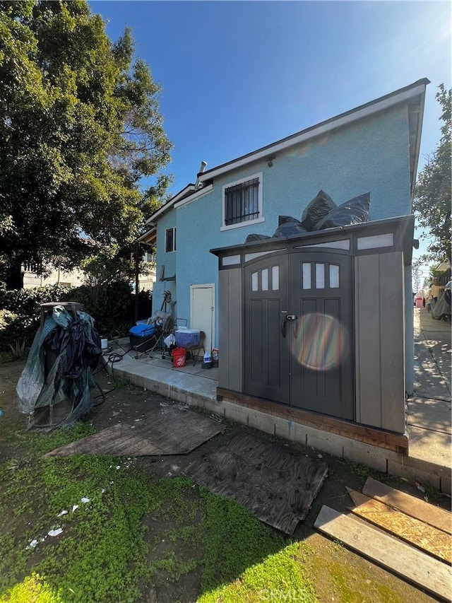 rear view of house with stucco siding and an outbuilding