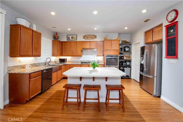 kitchen featuring light wood-type flooring, visible vents, a breakfast bar, a kitchen island, and appliances with stainless steel finishes