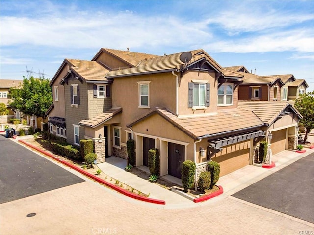 multi unit property featuring stucco siding, driveway, stone siding, a garage, and a tiled roof